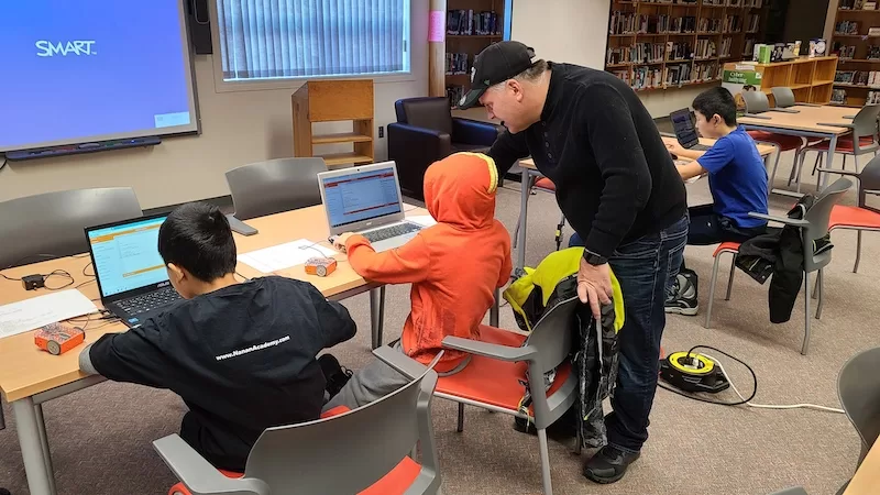 teacher helping student with coding lesson